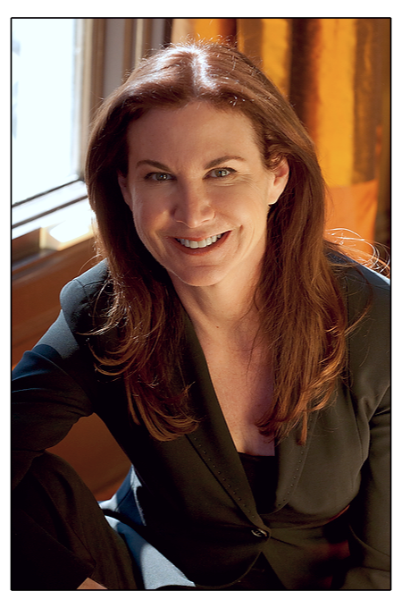 A woman with long red hair sitting in front of a window.